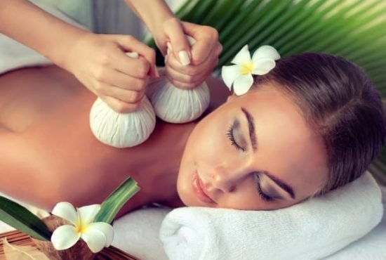 Young lady is laying on massage table and gets massage treatment.Spa and body massage.Woman is getting massage in the spa salon.